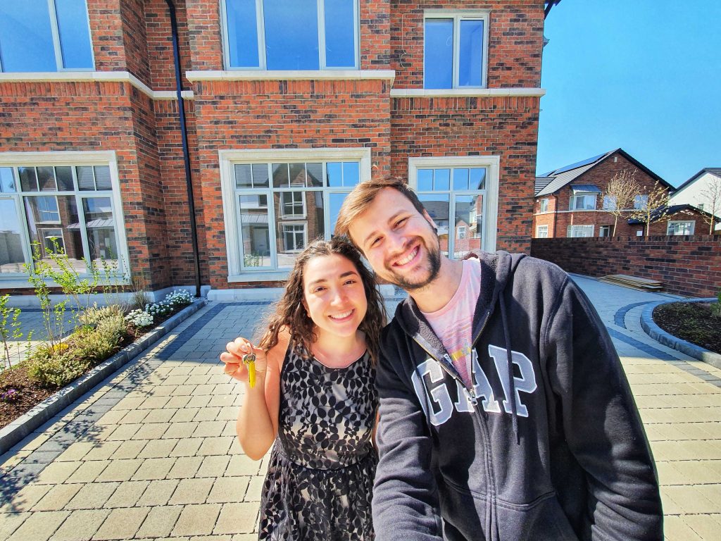 Couple smiling in front of a brick house