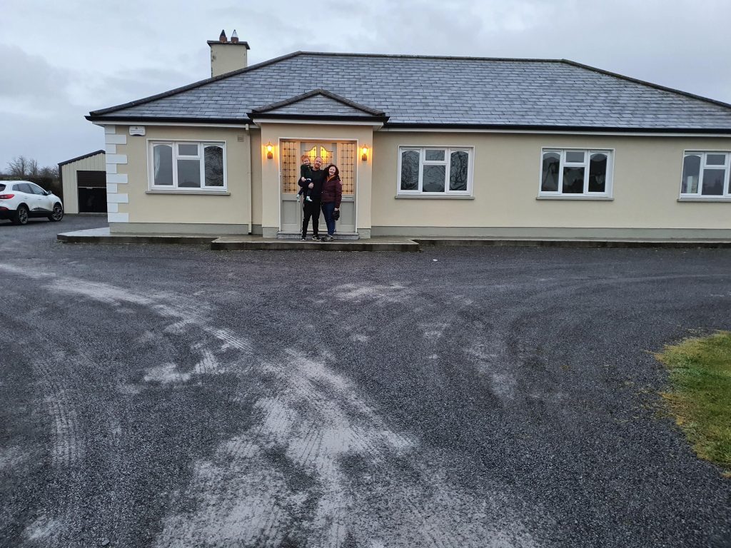 Two people standing in front of a bungalow house