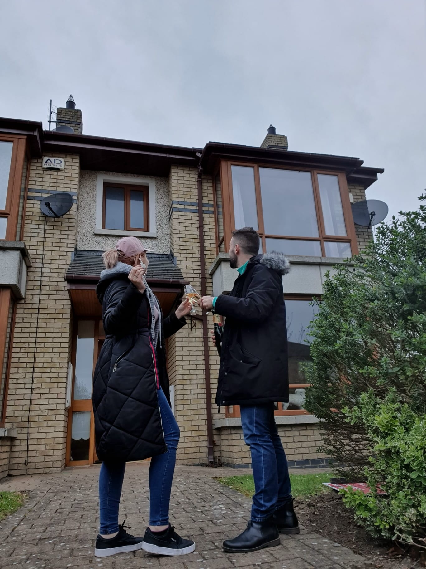 Two people exchanging keys outside a house