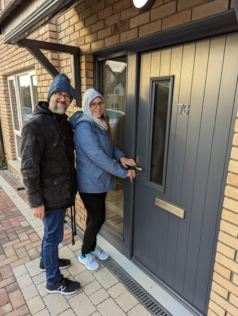 Couple standing by new house front door.