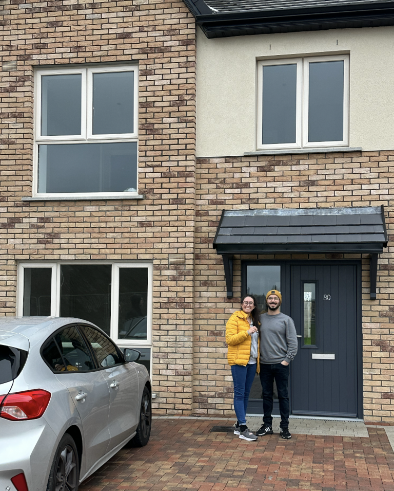 Couple standing in front of new brick house