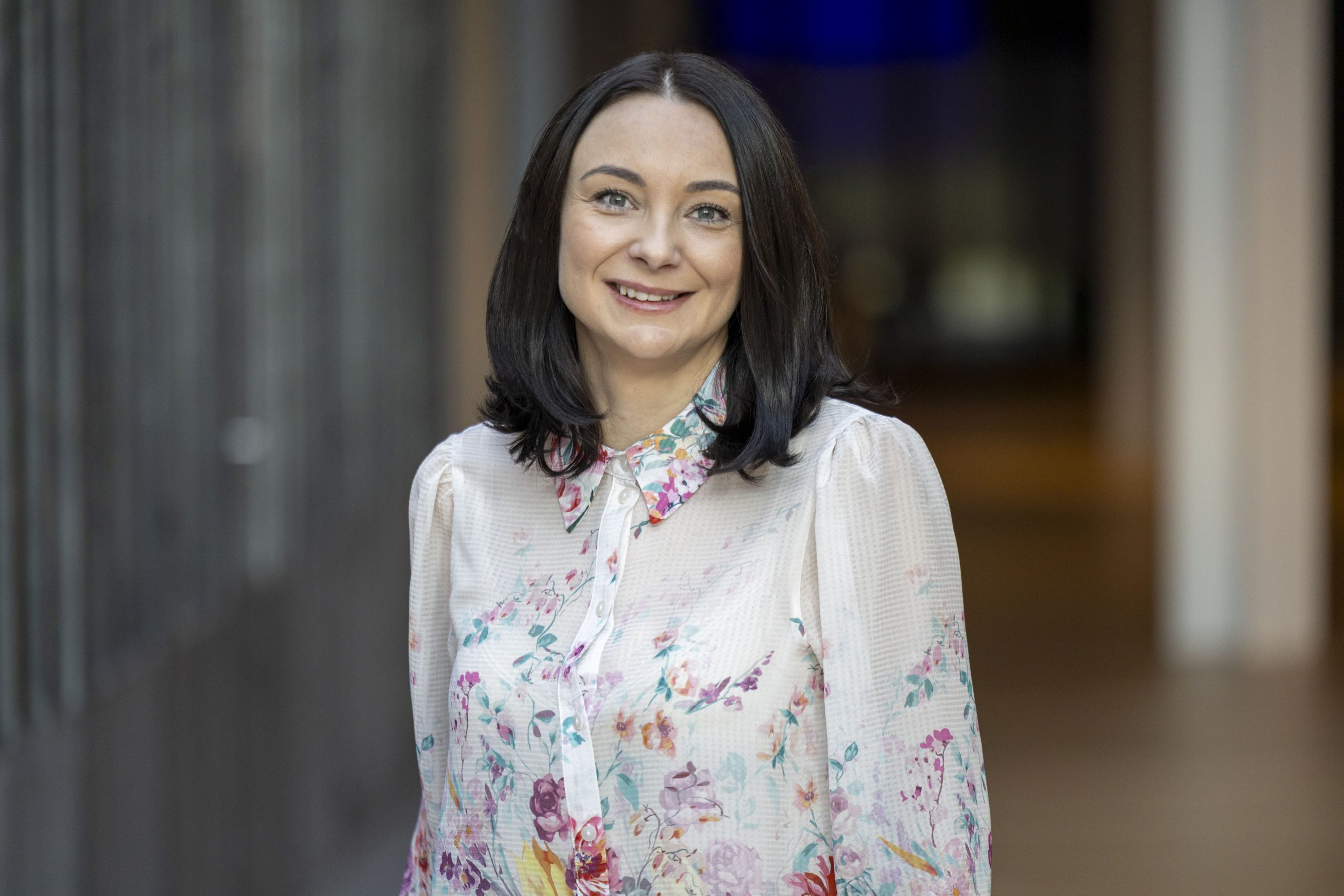 Professional woman smiling in floral blouse indoors